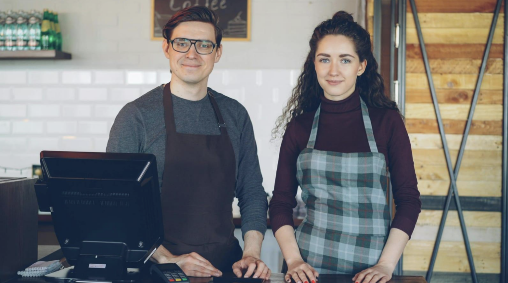 man and woman standing at register smiling